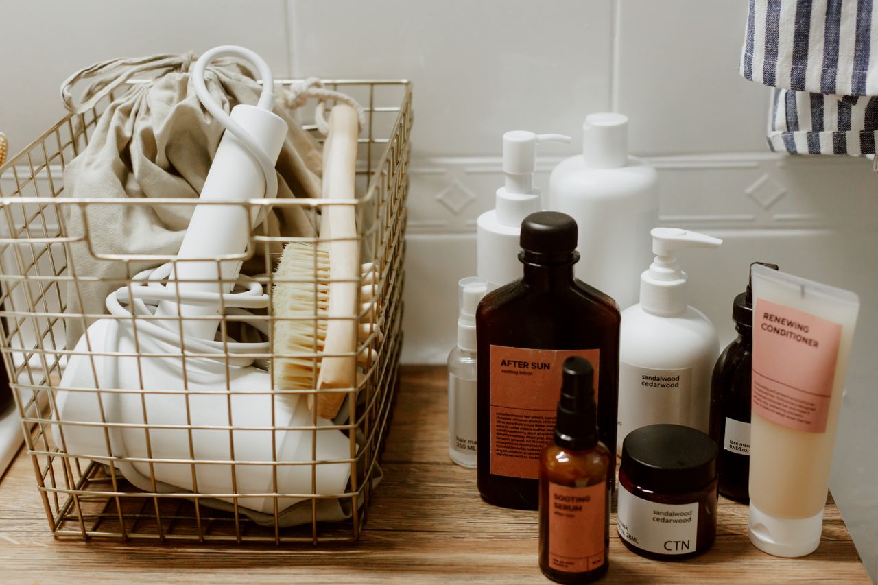 Neatly arranged bathroom toiletries and storage items on a wooden surface, featuring cosmetics and a hair dryer.