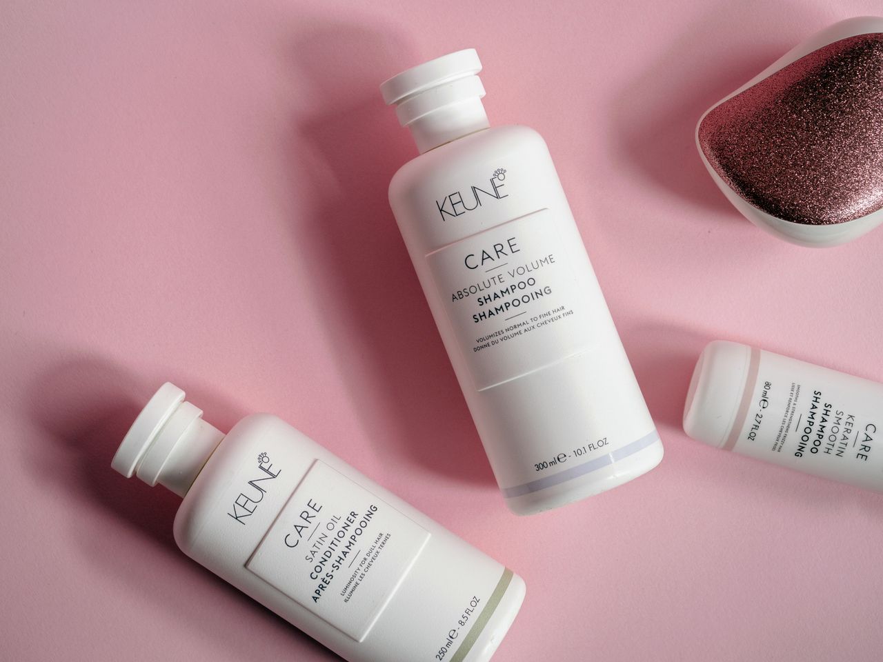 Elegant flat lay of shampoo and conditioner bottles on pink background, ideal for beauty brands.