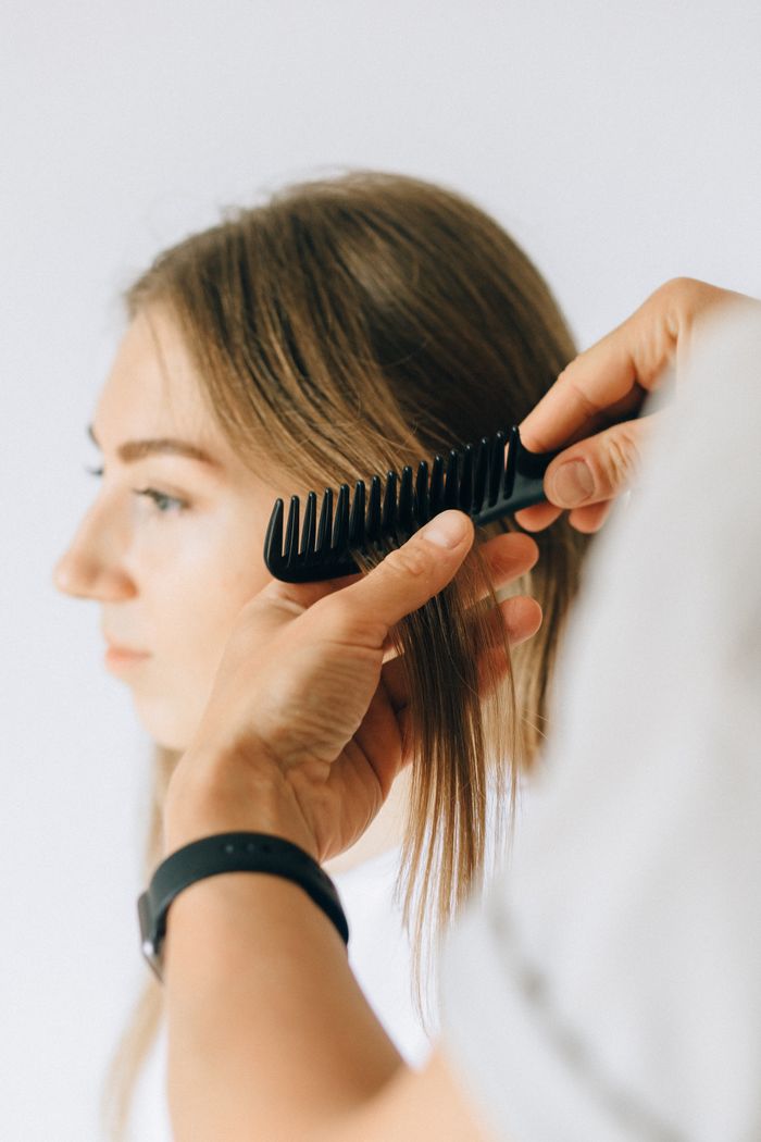 Mastering the First Impression: Your intriguing post title goes here Close-up of a woman receiving hair care and combing at a salon.